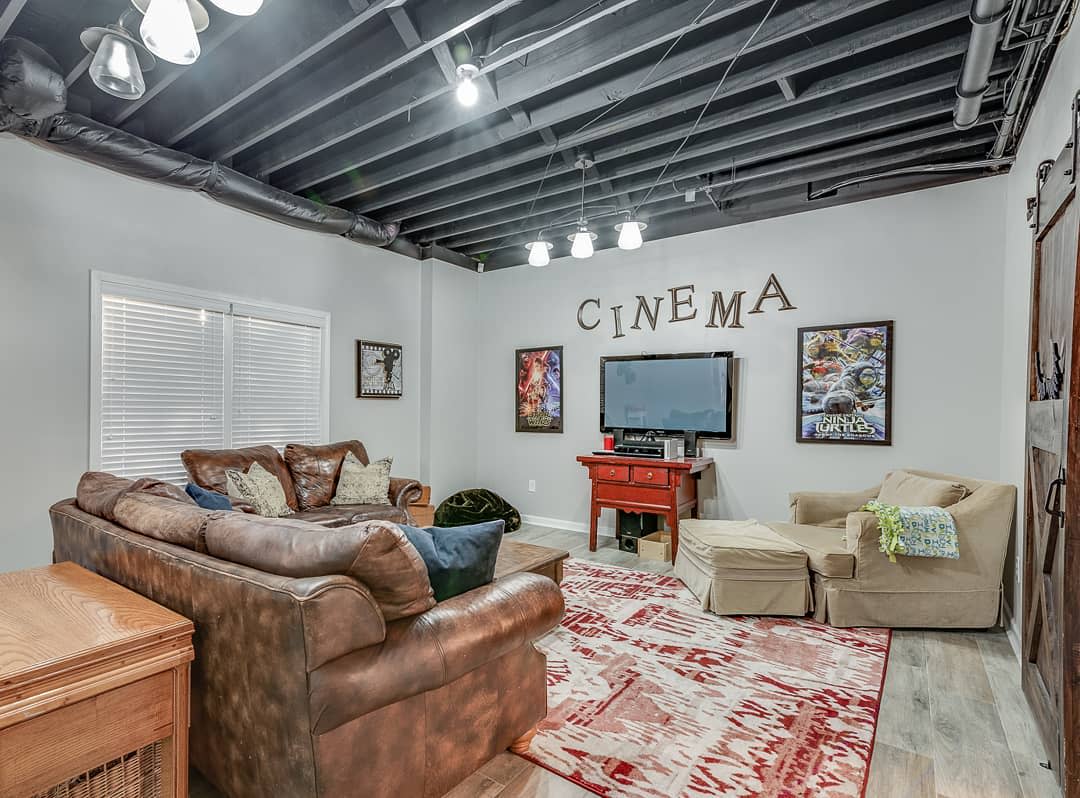 Basement home theater with leather sectional, movie posters, and cozy seating area.
